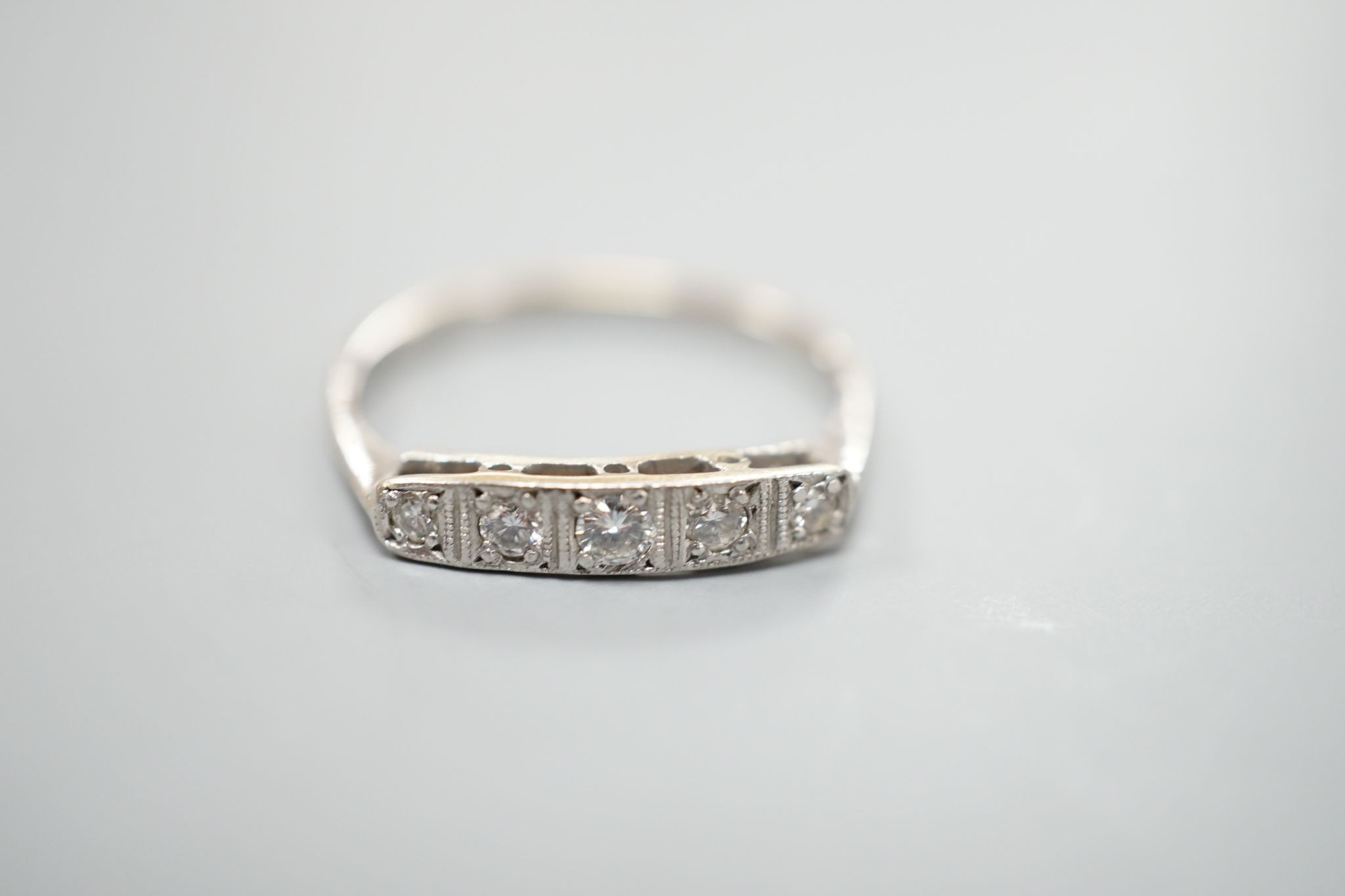 An 18ct and plat, graduated five stone diamond set half hoop ring, size N, gross weight 1.8 grams.